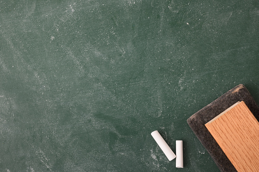 Erased and dirty class blackboard with white chalk and eraser close up. Top view