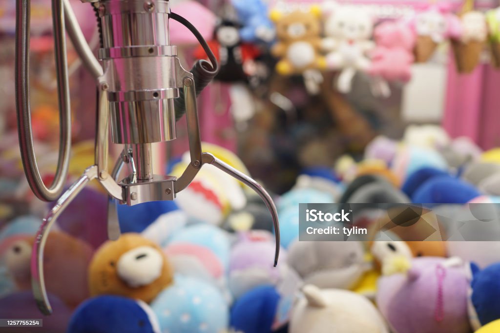Close up of the doll claw machine of games arcade in shopping mall The doll sold in coin operating machine by using joystick to control the clamp to pull the doll up. Toy Grabbing Game Stock Photo