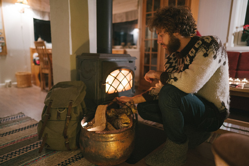 Man sitting near wood stove  in cozy cabin