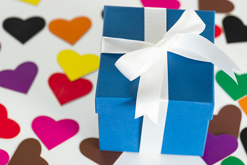 A blue gift box is on the colored heart shapes.