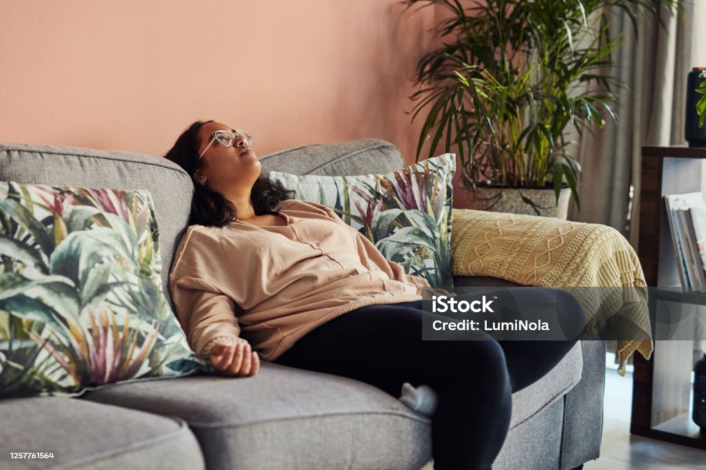 Lockdown getting you down? Shot of a young woman resting on the sofa at home Laziness Stock Photo