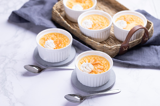 Creme caramel in the pots on a light marble table