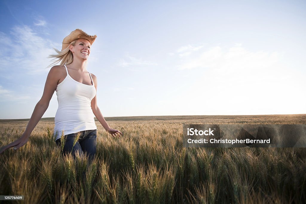 Cowgirl in esecuzione attraverso un campo di grano - Foto stock royalty-free di 20-24 anni