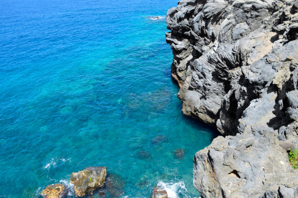 A high-angle, wide-view shot of the rugged volcanic coastline at the Los Abrigos Natural Pools (Piscinas Naturales Los Abrigos), located in the Granadilla de Abona municipality in the southeast of Tenerife, Canary Islands, Spain.