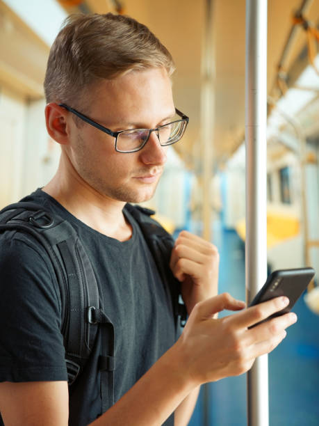 istock A man holds a phone in one hand while holding on to a handrail in an empty subway car with the other 1257769775