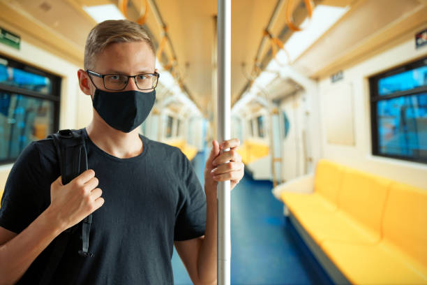 istock A man with a backpack rides in an empty subway car, holding on to the handrail and looking at camera 1257770335