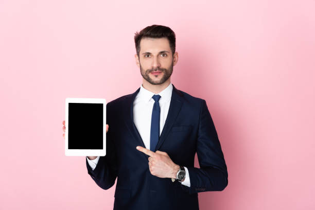 istock handsome businessman pointing with finger at digital tablet with blank screen on pink 1257771057