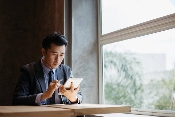 Young asian businessman working with digital tablet and stylus pen Young asian businessman working with digital tablet and stylus pen financial occupation stock pictures, royalty-free photos & images