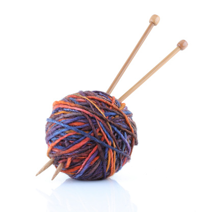 A ball of wool yarn with knitting needles