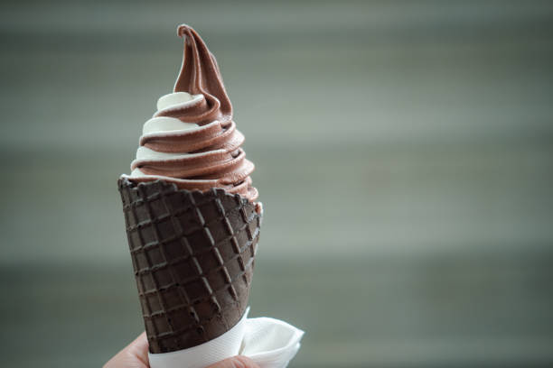 istock Hand holding mixed flavor soft cream in waffle chocolate cone 1257776476