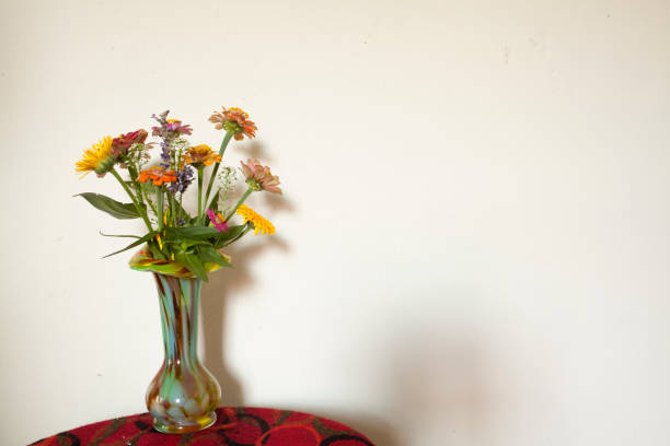 toy mini bucket with multi-colored flowers. on a light gray background in sunlight and shadow