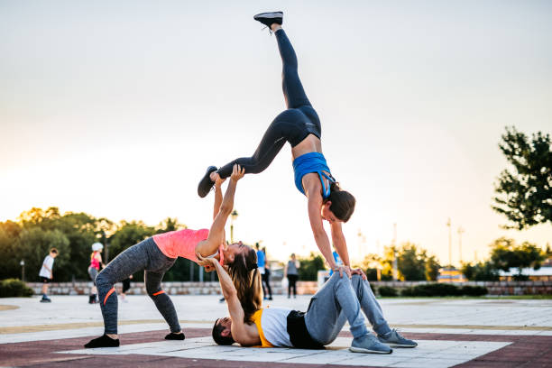 Two young women are practicing yoga at public park.