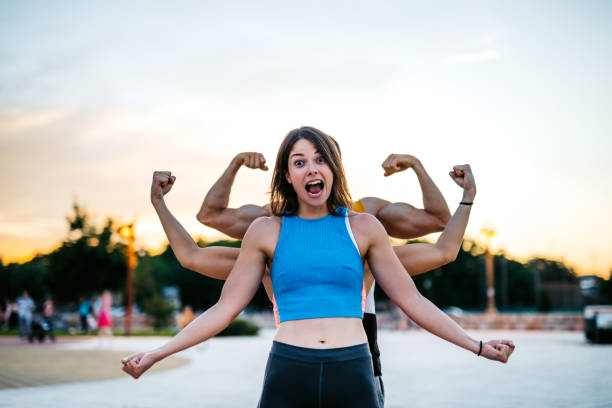 Caucasian young woman and her friends who standing behind her flexing biceps and showing off.