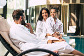 Happy beautiful family in bathrobes are joyful together while sitting in the spa salon