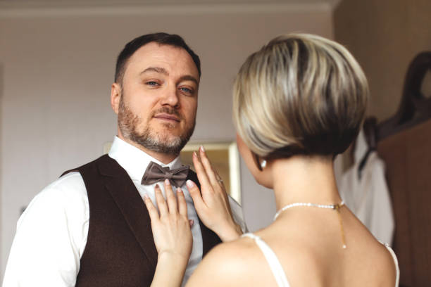 istock A woman puts a bow tie on a man. 1257787739