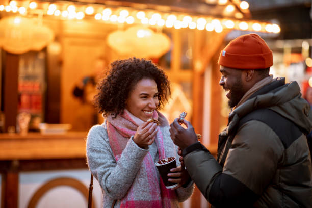 Wow! These Are Delicious! Two friends smile playfully towards each other as they eat sweet churros cooked freshly at the Xmas market in Newcastle upon Tyne. concession stand stock pictures, royalty-free photos & images