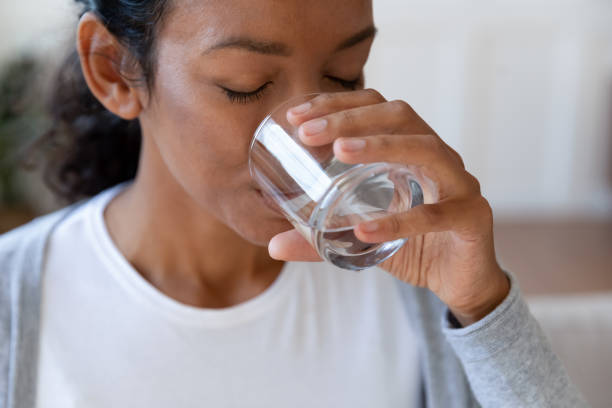 close up of african american woman drinking water - thirsty imagens e fotografias de stock