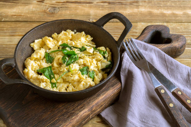 scrambled eggs with spinach in a cast-iron pan. scrambled eggs with spinach in a cast-iron pan. on a wooden table omelet rustic food food and drink stock pictures, royalty-free photos & images