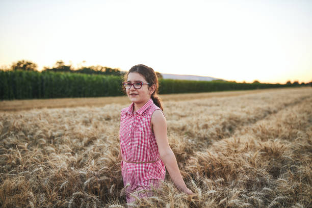 curious girl walking through wheat field and admiring the beauty of it - homegrown produce wheat organic crop imagens e fotografias de stock