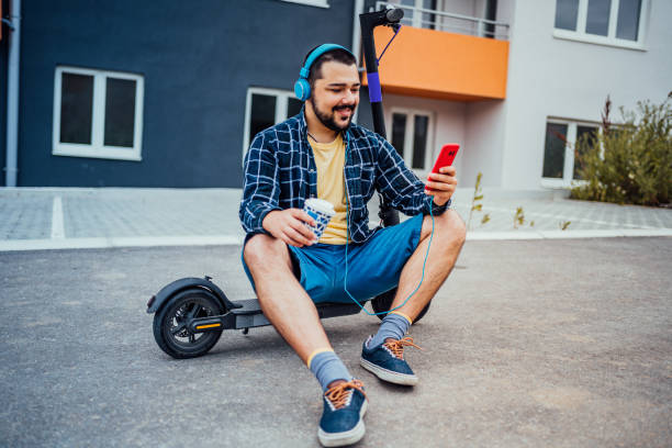 istock Man sitting on electric scooter and using phone 1257797560