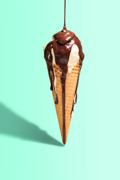 Vanilla ice cream cone with dripping chocolate. Ice cream with topping. Melted chocolate drip Vanilla ice cream cone with melted chocolate topping, isolated on green mint background, in harsh light. Summer dessert. Dripping chocolate sauce ice cream drips studio stock pictures, royalty-free photos & images