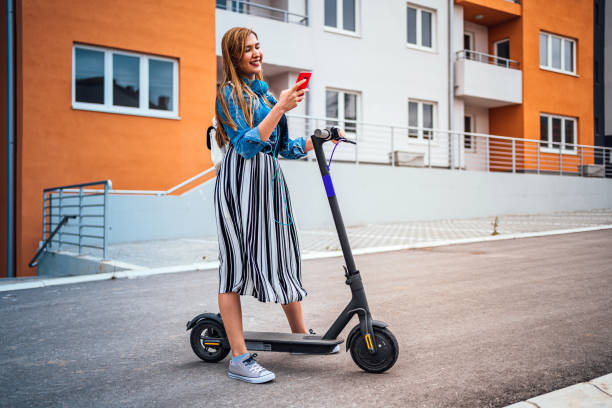 istock Woman with electric push scooter using phone 1257799698