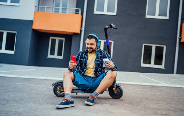 istock Man sitting on electric scooter and using phone 1257799715