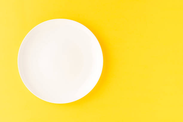 istock Overhead shot of blank white plate on yellow background. Flat lay 1257805604
