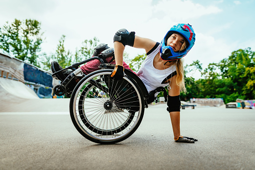 Mujer discapacitada en silla de ruedas haciendo acrobacias en el parque de patinaje después del encierro photo