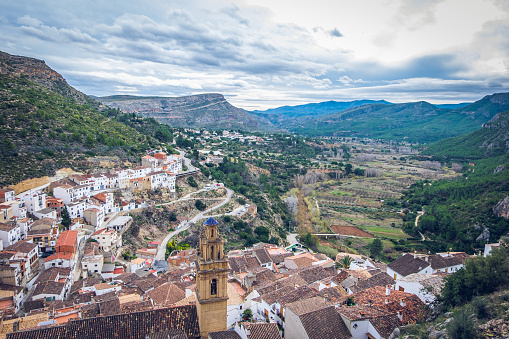 Village Chulilla from the top, rooftops and tower of church Inglesia de la Virgen de los Angeles, with mountain background. Los Serranos, Valencia, Spain.