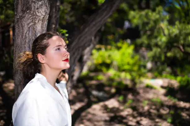 Young woman portrait closeup in yukata white spa bathrobe robe in outdoor garden in Japan with nature view