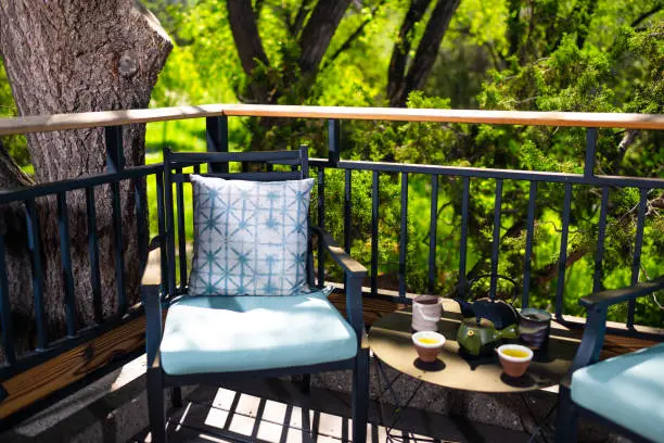 Couple of tea drinks by traditional teapot by fence railing in modern luxury outdoor garden in backyard of zen home romantic travel