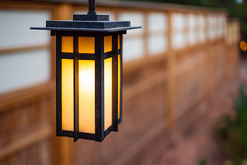 Japan hanging lantern lamp in Japanese garden with house temple wall blurry bokeh background and illuminated light in evening night