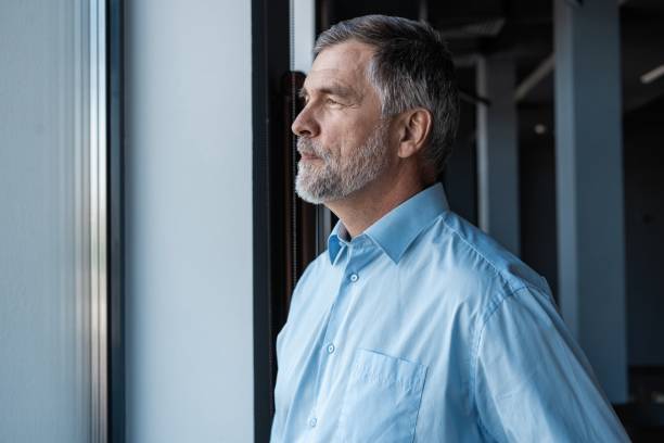 istock cheerful businessman looking at window while standing in office building. 1257814493