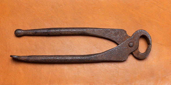 Old large pliers. Vintage rusty carpentry tool on leather surface