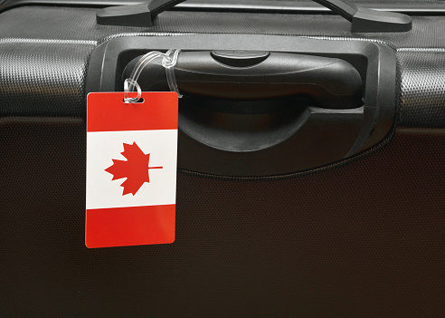 Closeup of a suitcase with a Canadian flag luggage tag on it symbolizing a Canadian traveller.