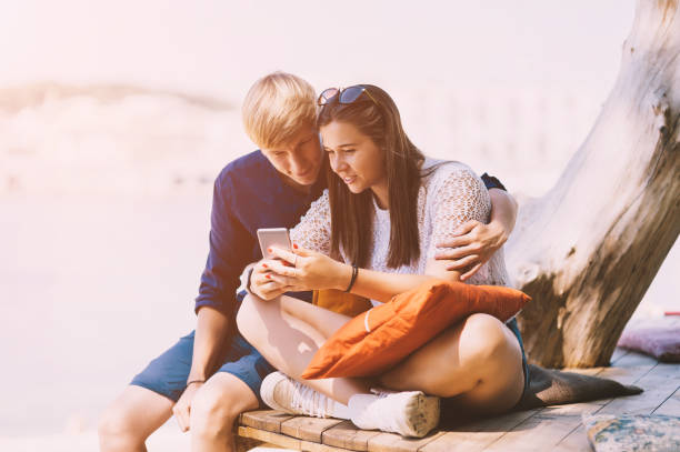 istock Young couple texting at the beach 1257824170
