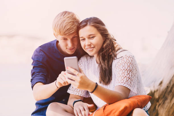 istock Young couple texting at the beach 1257824276