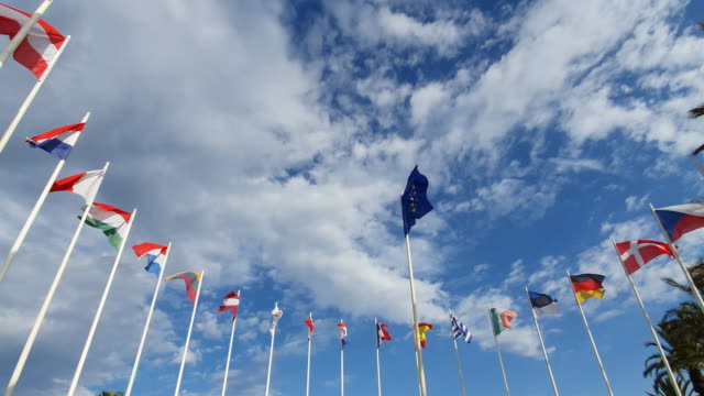Flags Of European Countries on Flagpoles against a cloudy sky