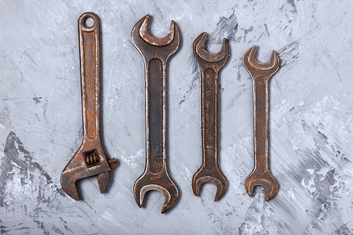 A set of large old wrenches on the concrete floor of the garage. Vintage locksmith tool