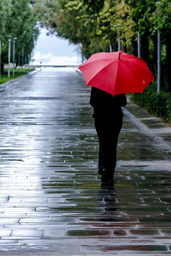 Woman with red umbrella walking on wet road in Turkey