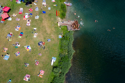 Aerial view of a beach at the lake with people swimming and sunbathing.