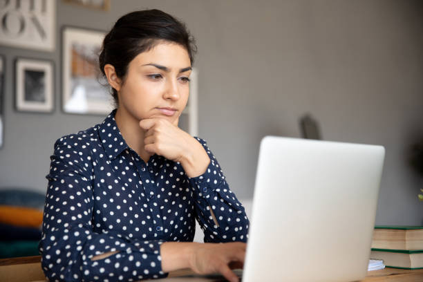 istock Thoughtful young indian woman looking at computer screen. 1257836725
