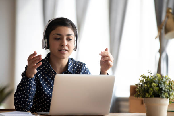 istock Focused young indian woman in earphones looking at computer screen. 1257836729