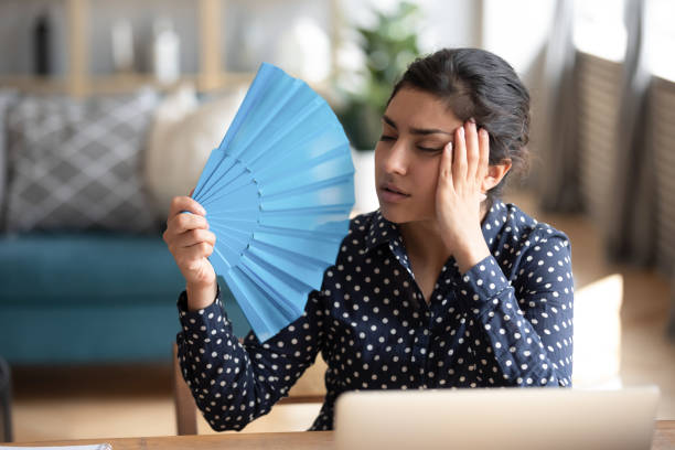 Young exhausted indian woman waving paper fan. Head shot young exhausted indian woman waving paper fan, suffering from high temperature at home. Tired overheated millennial hindu girl cooling herself, feeling unwell alone in living room. overheated photos stock pictures, royalty-free photos & images