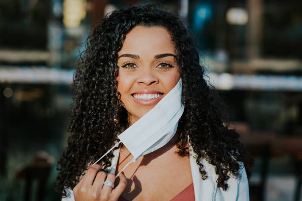 istock Woman removing face protection mask and smiling 1257836902