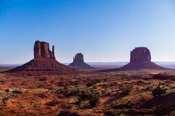 istock Famous butte formations with red rock in Monument Valley during twilight dark night in Arizona with moon moonlight blue hour sky panoramic view 1257838255