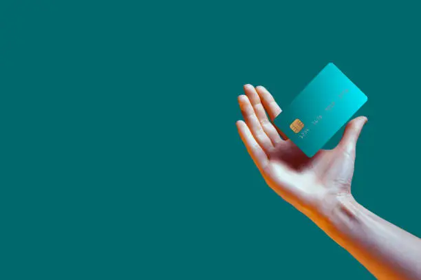 Photo of Close up female hand holds levitating template mockup Bank credit card with online service isolated on green background