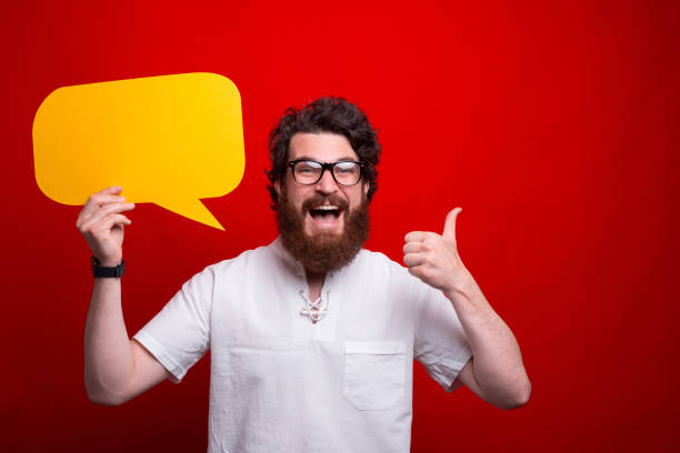 istock Excited bearded man is showing thumb up while holding a bubble speech 1257842595