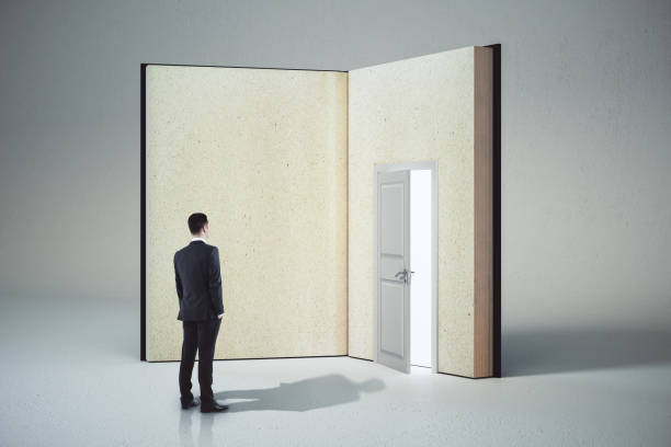 istock Bsinessman looking at abstract open book with door on white background. 1257842711